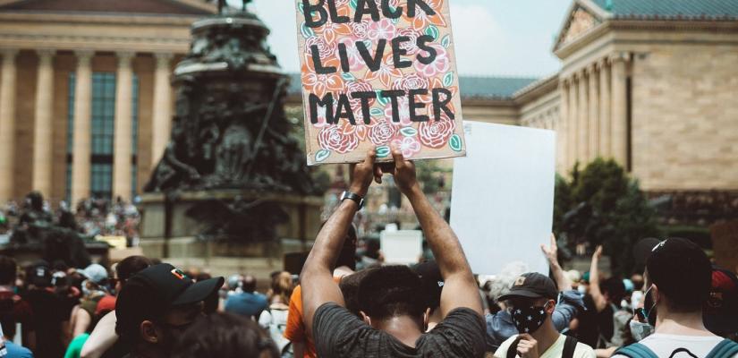 Een man houdt een bord vast met Black Lives Matter