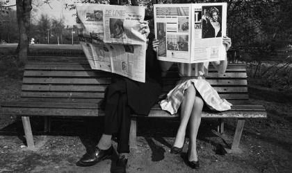 Een tweetal op een bank leest de krant, zwartwitfoto