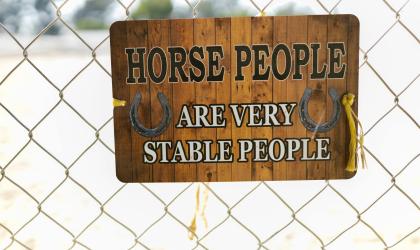 Bord met tekst: 'Horse people are very stable people' tegen hek