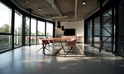 een vergaderzaal met lege tafel en stoelen voor een raam