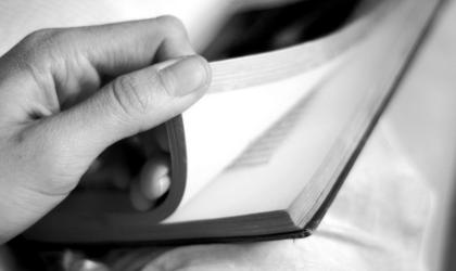 Zwart-wit close-up van een hand die boekpagina's omslaat